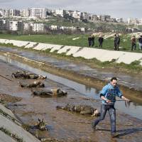 A Syrian passes dead bodies along a river in the Bustan al-Qasr neighborhood of Aleppo in January 2013. All-out effort to crush moderate Syria rebels may leave Obama successor with 'problem from hell'