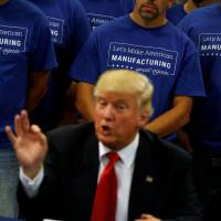 Workers stand behind Republican presidential nominee Donald Trump during a business roundtable at the Staub Manufacturing plant in Dayton, Ohio, Wednesday. Trump threatens to derail Cuba detente, enters spending bill fray, calls Fed rate policy 'politics'