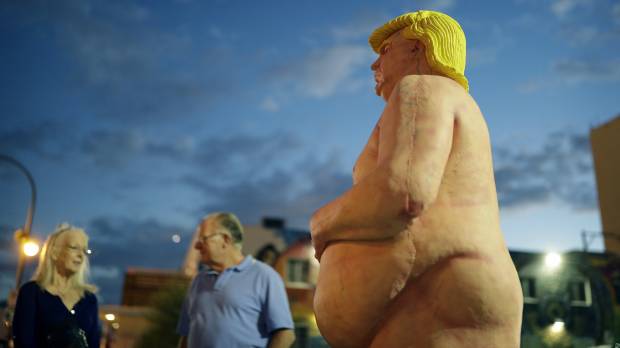 People look at a statue of a naked Republican U.S. presidential candidate Donald Trump in Las Vegas on Wednesday. The statue was knocked down and sprayed with graffiti, and removed Friday. Police search for culprits after naked Donald Trump statue is stolen in Miami