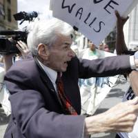 Jerry Lambert (left), a supporter of Republican U.S. presidential nominee Donald Trump, and Asa Khalif, with Black Lives Matter, scuffle after Khalif took Lambert's sign outside the location where Trump was to meet African-American business and civic leaders in Philadelphia on Friday. Trump surrogate warns of taco trucks on every corner if GOP loses