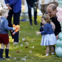 Britain's Prince William and Princess Charlotte look on as Prince George plays with a bubble gun at a children's party at Government House in Victoria, British Columbia, Thursday. U.K. royal kids make rare party showing in Victoria, balloons and all