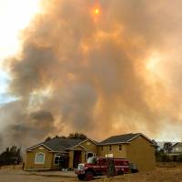 A helicopter drops water on flames as they approach a home in the Santa Cruz Mountains near Loma Prieta, California, Tuesday. The Loma Fire has charred more than 1,000 acres and burned multiple structures in the area. Heat wave causes California wildfire to worsen, threatening homes