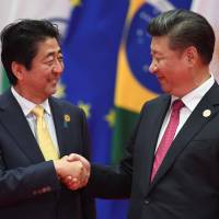 Prime Minister Shinzo Abe poses with Chinese President Xi Jinping before the Group of 20 leaders' family photo in Hangzhou, China, on Sunday. World leaders converged on the city for the two-day G-20 leaders' summit. As G-20 leaders gather for summit, all eyes on Abe and Xi