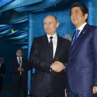 Prime Minister Shinzo Abe shakes hands with Russian President Vladimir Putin while visiting an oceanarium on Russky Island, Russia, on Saturday. POOL / via AP China's rise, Russia's shaky ties with West shape contents of Abe-Putin summit in Vladivostok