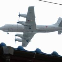 A Maritime Self-Defense Force aircraft flies over a house in Yamato, Kanagawa Prefecture, in May 2014. Supreme Court likely to reject lawsuit on halting U.S. military flights at Atsugi base over noise