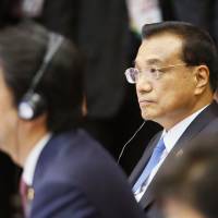 Chinese Premier Li Keqiang (right) and Prime Minister Shinzo Abe listen to speeches during the ASEAN Plus Three summit in Vientiane on Wednesday. Japan pushing 'quality' aid to counter China's clout in ASEAN