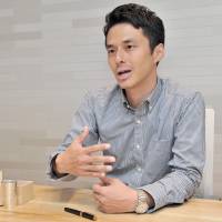 Keigo Omaki talks about his effort to document Japan's traditional craftsmen online, during an interview in Tokyo on Aug. 25. Before him is a pewter cup made by Keiichi Nakamura, one of the craftsmen featured in the video project. Champion of craftsmen on mission to showcase Japan's masters online
