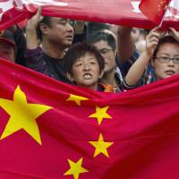 Chinese demonstrators hold national flags while marching on a street during a protest against Japan in Chengdu, China, in September 2012. 80% of Japanese fear military clash around Senkakus, poll finds