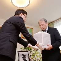 A Hokkaido government official hands the remains of former Imperial Japanese Army soldier Shigeichi Idoi to his younger brother, Tsuyoshi, and other family members Thursday in Otaru, Hokkaido. The remains were discovered last year on the Kuril island of Shumshu in Russia. Otaru kin receive remains of Japanese killed in fierce post-surrender Kuril battle in 1945
