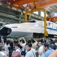 Rail fans flock to see a shinkansen locomotive lifted by cranes for maintenance work Sunday at a plant operated by Central Japan Railway Co. (JR Tokai) in Hamamatsu, Shizuoka Prefecture. Last public viewing of shinkansen-hoisting work held at JR Tokai plant