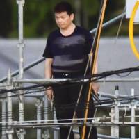 Yasuhide Mizobata brandishes two handguns on scaffolding in the city of Wakayama on Wednesday. Details emerge of Wakayama armed standoff