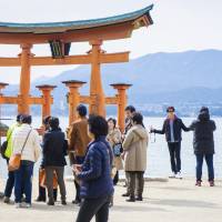 Chinese tourists take photos of a traditional Japanese shrine gate at Miyajima, Hiroshima Prefecture, in March. Number of foreign visitors to Japan sets August record of 2.04 million