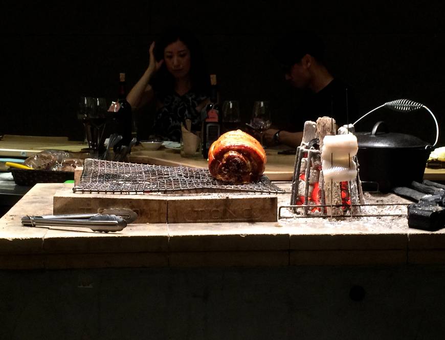 Falo Center of attention: Porchetta (rolled pork) slowly cooks over the charcoal grill that acts as the centerpiece of the open kitchen at Falo. Customers sit at the wooden counter that runs along all four sides. | ROBBIE SWINNERTON