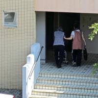 Senior citizen care needs to step up: A caregiver accompanies an elderly woman to her apartment in Inzai, Chiba Prefecture. For elderly residents, city life doesn't get old