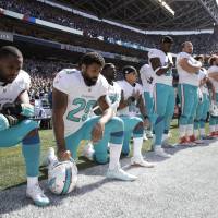 Dolphins players Jelani Jenkins (left), Arian Foster (second from left), Michael Thomas (third from left) and Kenny Stills kneel during the national anthem on Sunday in Seattle. More NFL players protest during U.S. national anthem