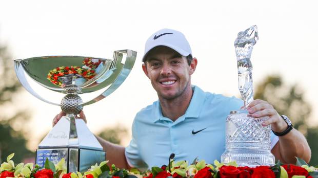 Rory McIlroy poses with the FedEx Cup (left) and the Tour Championship trophy after winning both on Sunday in Atlanta. McIlroy walks away with two prizes