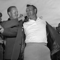 Arnold Palmer gets help from Jack Nicklaus as he slips on his green jacket after winning the Masters on April 12, 1964. Palmer, who died at age 87 on Sunday, won seven major titles during his career. Legendary golfer Arnold Palmer dies at 87