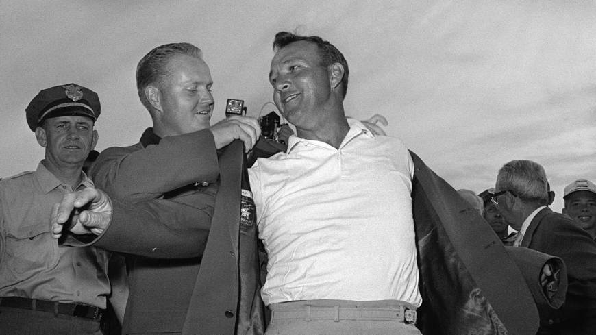 Arnold Palmer gets help from Jack Nicklaus as he slips on his green jacket after winning the Masters on April 12, 1964. Palmer, who died at age 87 on Sunday, won seven major titles during his career. Legendary golfer Arnold Palmer dies at 87