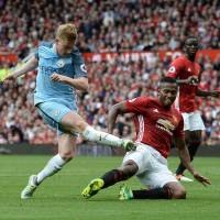Manchester City's Kevin De Bruyne (left) shoots during his team's 2-1 win over Manchester United at Old Trafford on Saturday. City edges United in derby clash