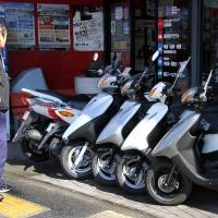 A passerby looks at Yamaha Motor Co. scooters outside a dealership in Tokyo. Honda, Yamaha in talks on moped tie-up