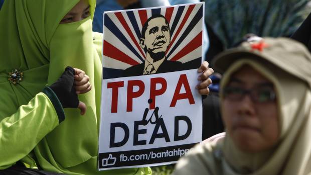 A Malaysian protester poses while holding a placard opposing the Trans-Pacific Partnership agreement and bearing U.S. President Barack Obama's image at a demonstration in Kuala Lumpur in January. Trade deals Trump loves to hate actually have small positives and definite negatives