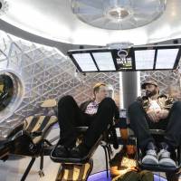 SpaceX CEO Elon Musk (left) talks with guests in a mock-up of the SpaceX Dragon V2 spacecraft in May 2014 at the company's headquarters in Hawthorne, California. SpaceX's Elon Musk turns to science fiction in naming Mars ship, other hardware