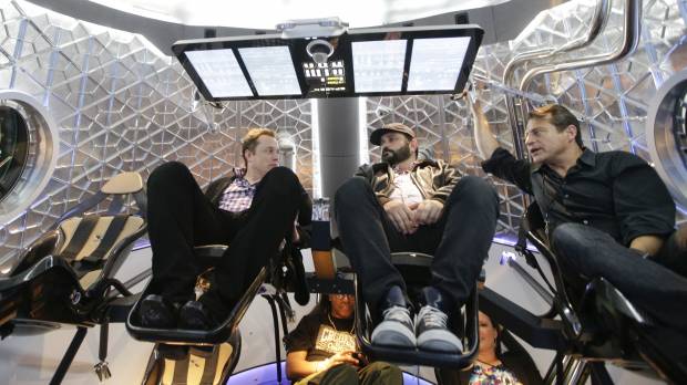 SpaceX CEO Elon Musk (left) talks with guests in a mock-up of the SpaceX Dragon V2 spacecraft in May 2014 at the company's headquarters in Hawthorne, California. SpaceX's Elon Musk turns to science fiction in naming Mars ship, other hardware