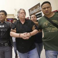 Thai police officers escort a suspect (center) at a Bangkok police station on Sept. 24 after three men were arrested on charges of trafficking in forged passports and concealing a dismembered body at an apartment in the Thai capital. Accused American passport forger in Bangkok 'confesses' to dismembering dead man