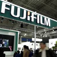 Signage from Fujifilm Holdings Corp. hangs over its booth at the CP+ Camera and Photo Imaging Show in Yokohama in February. Fujifilm will reportedly buy Takeda Pharmaceutical Co.’s research chemical unit to improve its medical business. Fujifilm to buy Takeda's research chemical arm: sources