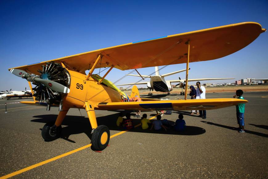 People look at q vintage Boeing-Stearman Model 75 biplane as it sits on the runway Sunday at Khartoum airport during the Vintage Air Rally (VAR). A dozen biplanes from the 1920s and 1930s are flying 8,000 miles from Crete to Cape Town in a vintage aviation rally that harks back to the early days of air travel. The pilots will fly along the Nile from Cairo to Khartoum, past the highlands of Ethiopia, down through East Africa past Mount Kilimanjaro, over Victoria Falls, and will end in South Africa.
