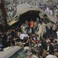 Volunteers carry an injured passenger from the wreckage of a train that crashed into another train in Karachi, Pakistan, Thursday. Faulty signal suspected as Karachi train station crash kills at least 16