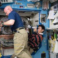 This NASA file photo shows NASA astronaut Scott Kelly and assistant Japan Aerospace Exploration Agency astronaut Kimiya Yui with measurements for the ongoing Ocular Health study. Spinal fluid changes in space may blur vision of astronauts, study finds