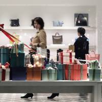 Christmas decorations sit in a window display as shoppers browse in a luxury handbag and shoe store in the Marunouchi area of Tokyo on Dec. 19. Household spending drops for ninth consecutive month