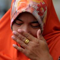 A woman wipes away tears as she offers prayers to loved ones at a mass grave in Aceh on Monday. It was on Dec. 26, 2004, that the Indian Ocean tsunami, which devastated Aceh province in one of the worst natural disasters in human history, occurred. Indonesians remember loved ones on 12th anniversary of devastating Indian Ocean tsunami