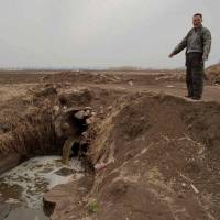This May 2016 picture shows local farmer Ren Xiangjun pointing to a pipe carrying waste water into the surrounding farm fields in front of a dairy farm in Gannan county, Heilongjiang province. The price of milk: China's giant cow farms leave neighbors up polluted creek