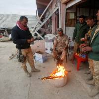 Peshmerga forces warm themselves by a fire in the town of Bashiqa, after it was recaptured from the Islamic State, east of Mosul, Wednesday. 2,000 Iraqi forces killed in month's fighting to retake Mosul