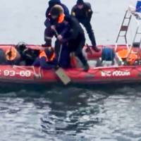 In this frame grab provided by the Russian Emergency Ministry Press Service, ministry employees lift a fragment of a plane outside Sochi, Russia, Monday. All 84 passengers and eight crew members on the Russian military’s Tu-154 plane are believed to have died Sunday morning when it crashed two minutes after taking off from the southern Russian city of Sochi. Kremlin downplays terror attack in Sochi jetliner crash despite wide debris field, airport security concerns