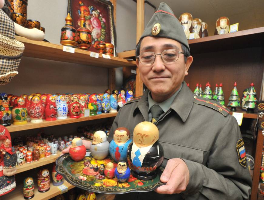 Kazuharu Iwahashi, owner of the Russian Tea specialty shop in Taito Ward, Tokyo, holds matryoshka dolls featuring past Russian leaders on Nov. 23.