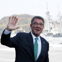 U.S. Defense Secretary Ash Carter waves to reporters on the deck of the Izumo, the Maritime Self-Defense Force’s helicopter carrier, at its base in Yokosuka, Kanagawa Prefecture, on Tuesday. Outgoing U.S. defense chief tours Japan's largest naval vessel