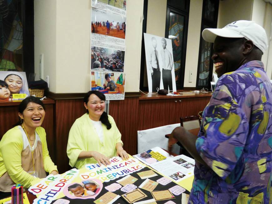 Amnesty International Japan volunteers chat to a visitor at their stall.