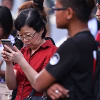 Chen Peijie, China’s consul-general in Sabah, checks her mobile phone at a jetty in Kota Kinabalu in Borneo state on Sunday. She was awaiting news after a tourist boat carrying 28 Chinese nationals was reported missing the previous day. Chinese tourists missing after marine accident off Malaysian island are found alive