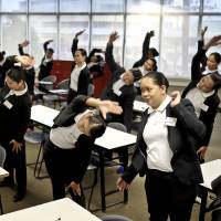 Trainee housekeepers do stretching exercises during a training session at the Magsaysay Center for Hospitality and Culinary Arts in Manila on Dec. 19. They are set to begin work in Japan in the spring. Learning to bow: Japan reluctantly opens door to foreign housemaids