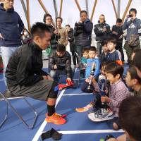 Amputee triathlon athlete Kenshiro Nakayama (left) interacts with children participating in a running workshop at the Shin-Toyosu Brillia Running Stadium in Tokyo’s Toyosu district on Dec. 10. Advanced tech used by Paralympic athletes could throw perception of disabilities into question