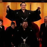 New yokozuna Kisenosato (top) raises his arms in celebration as his sumo stablemates lift him up after a ceremony in Tokyo on Wednesday. Kisenosato becomes first Japanese-born yokozuna in almost two decades