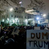 Protesters hold up signs against U.S. President Donald Trump in front of the U.S. Consulate General in the port city of Hamburg, northern Germany, on Tuesday. Criticism of Germany puts Trump administration on collision course with EU