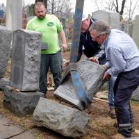 Workers (from left) Spencer Pensoneau, Ron Klump and Philip Weiss (of Weiss and Rosenbloom Monument company right toppled Jewish headstones after a weekend vandalism attack on Chesed Shel Emeth Cemetery in University City, a suburb of St Louis, Tuesday. Muslim groups, J.K. Rowling join in support to mend vandalized Jewish cemetery near St. Louis