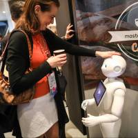An attendee interacts with SoftBank Group Corp.’s Pepper humanoid robot on the second day of the Mobile World Congress in Barcelona, Spain, on Tuesday. SoftBank Robotics plans app store for humanoid Pepper robot