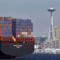 The Space Needle towers in the background beyond a container ship anchored in Elliott Bay near downtown Seattle. U.S. employers are thought to have hired at a brisk pace in February. U.S. adds a robust 235,000 jobs in February; unemployment dips to 4.7 percent