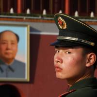 A paramilitary policeman looks back as he stands guard in Beijing’s Tiananmen Square near a giant portrait of late Chinese Communist Party Chairman Mao Zedong on Friday. China lawmakers add defaming Communist Party 'heroes' to civil code offenses