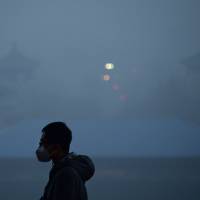 A man wears a mask while visiting a park amid heavy air pollution in Beijing in December. China can avoid 3 million premature deaths each year if. it slashes a type of fine particle air pollution to U.N recommended levels, a study said Wednesday. Curbing China's particulate smog can save 3 million lives a year, study finds